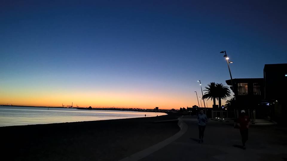 Lungomare al tramonto con due runner
